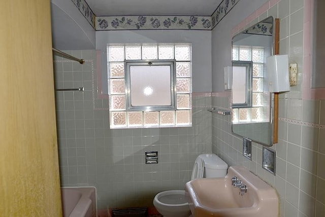 bathroom with a sink, tile walls, and toilet