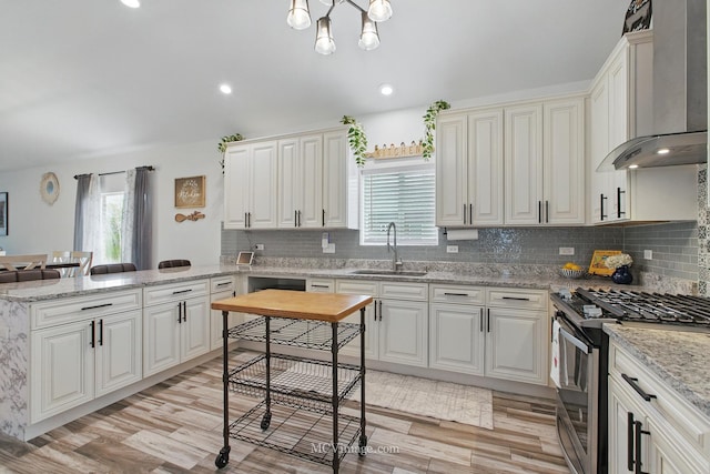 8566 S 83rd Ave, Hickory Hills, IL 60457 - kitchen featuring light wood finished floors, a sink, gas range, a peninsula, and wall chimney exhaust hood