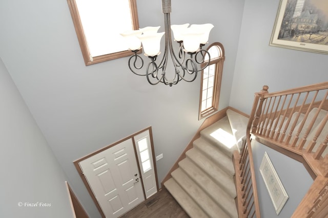 foyer entrance featuring wood finished floors, a chandelier, a high ceiling, and stairs