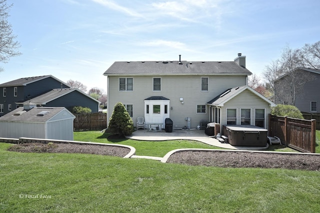 back of house featuring a fenced backyard, a hot tub, a storage shed, a patio area, and a lawn