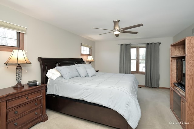 bedroom featuring light colored carpet, ceiling fan, and baseboards