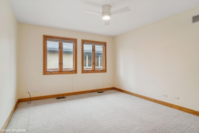 spare room featuring baseboards, visible vents, a ceiling fan, and light colored carpet
