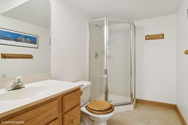 bathroom featuring toilet, a stall shower, vanity, baseboards, and tile patterned flooring