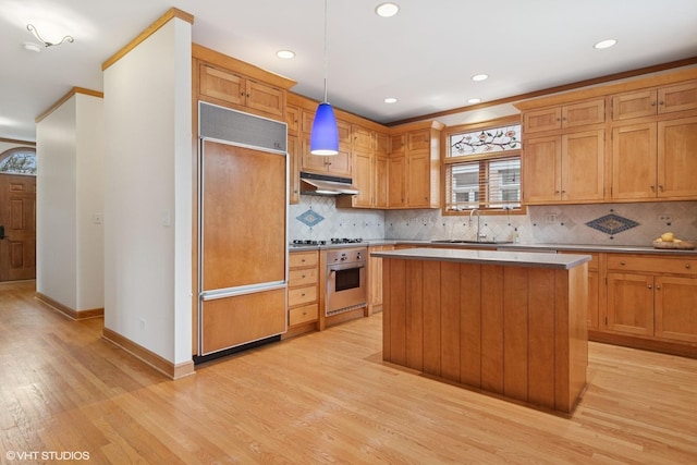 kitchen with light wood-style flooring, a sink, tasteful backsplash, stainless steel oven, and paneled built in refrigerator