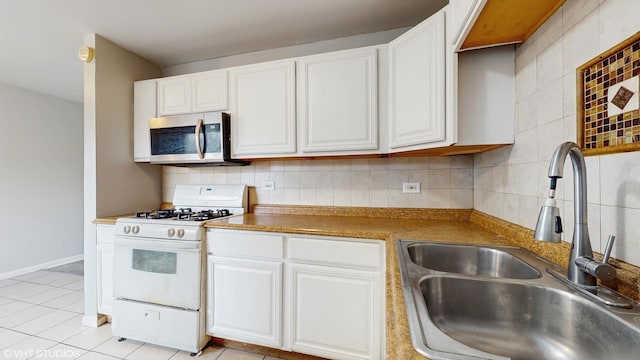kitchen featuring stainless steel microwave, white range with gas stovetop, a sink, and white cabinetry