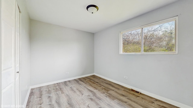 unfurnished room featuring baseboards, visible vents, and wood finished floors