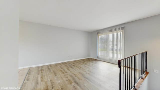 spare room featuring baseboards and wood finished floors