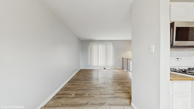 unfurnished living room with wood finished floors and baseboards