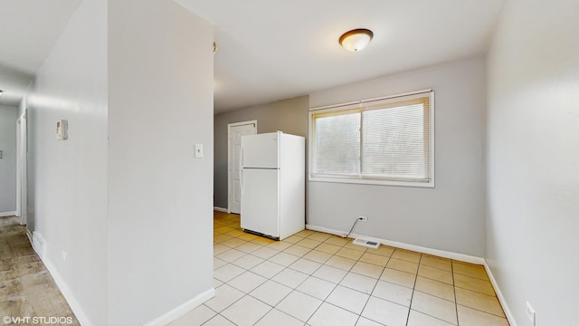 kitchen with baseboards, visible vents, and freestanding refrigerator