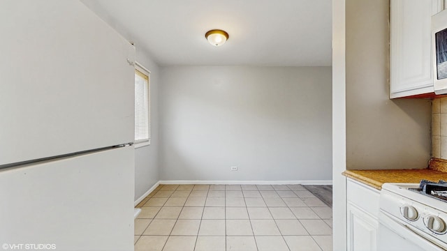 unfurnished dining area featuring light tile patterned flooring and baseboards