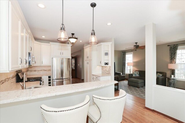 kitchen with a ceiling fan, a peninsula, a wealth of natural light, and stainless steel appliances