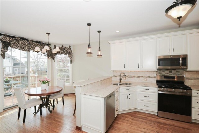 kitchen with a sink, backsplash, stainless steel appliances, and a peninsula