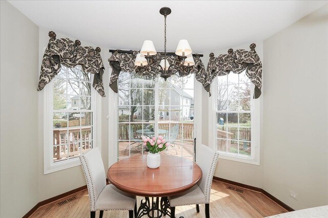 dining room featuring baseboards, visible vents, light wood-type flooring, and a chandelier
