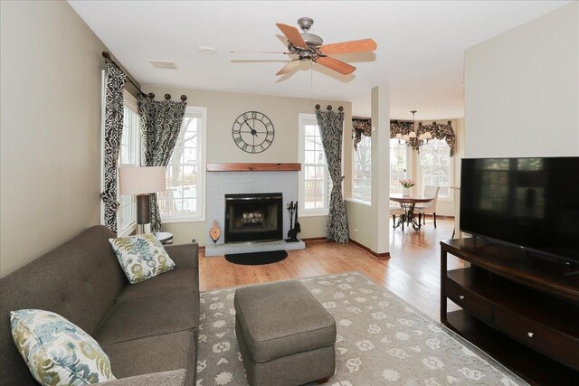 living area featuring a brick fireplace, visible vents, plenty of natural light, and wood finished floors