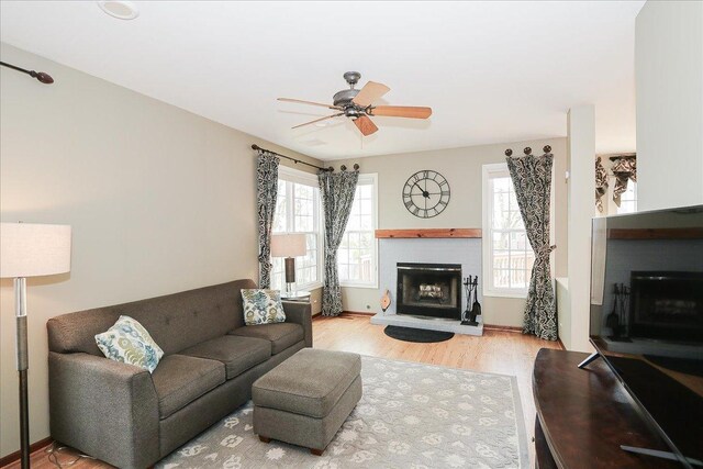 living room with a healthy amount of sunlight, ceiling fan, a brick fireplace, and wood finished floors