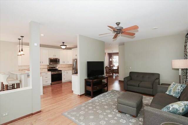 living room with a ceiling fan and light wood-type flooring