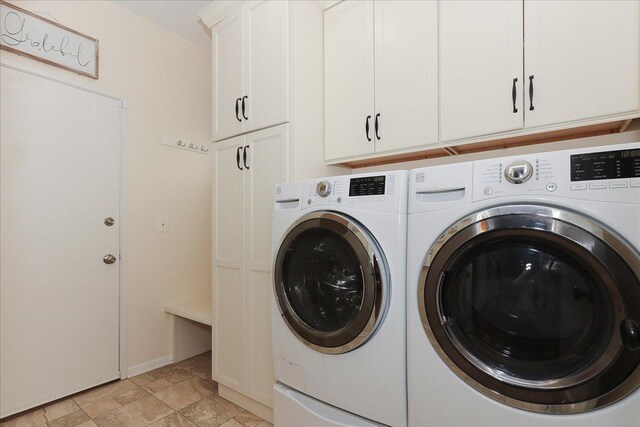 washroom with cabinet space, separate washer and dryer, baseboards, and stone finish floor