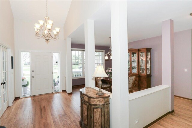 foyer entrance with an inviting chandelier, baseboards, and light wood-type flooring