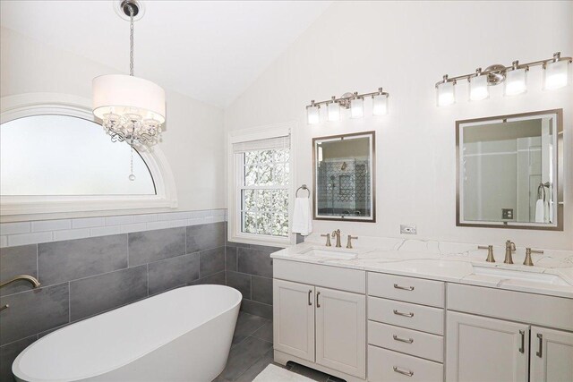 full bath featuring a sink, lofted ceiling, tile walls, and a soaking tub