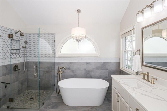 full bath featuring vanity, a chandelier, a freestanding bath, and a stall shower