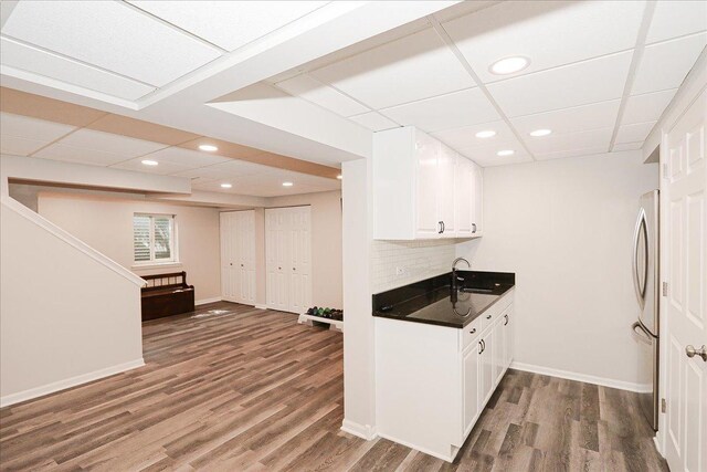 kitchen featuring dark countertops, a sink, freestanding refrigerator, white cabinetry, and wood finished floors
