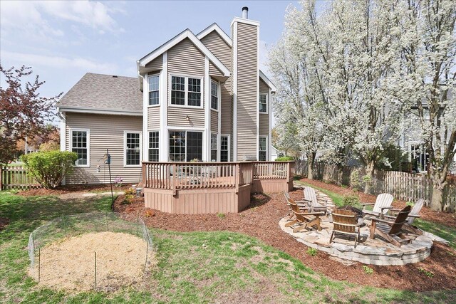 back of property featuring fence, a wooden deck, a chimney, and an outdoor fire pit