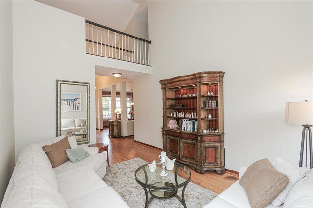 living area with baseboards, wood finished floors, and a high ceiling