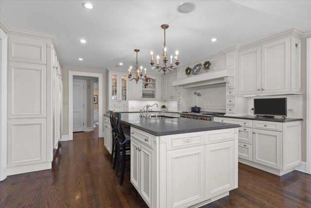 1300 Hackberry Ln, Winnetka, IL 60093 - kitchen featuring dark countertops, a chandelier, a sink, decorative backsplash, and white cabinetry