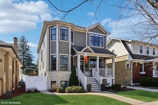 view of front facade featuring stairs, a front yard, covered porch, and fence