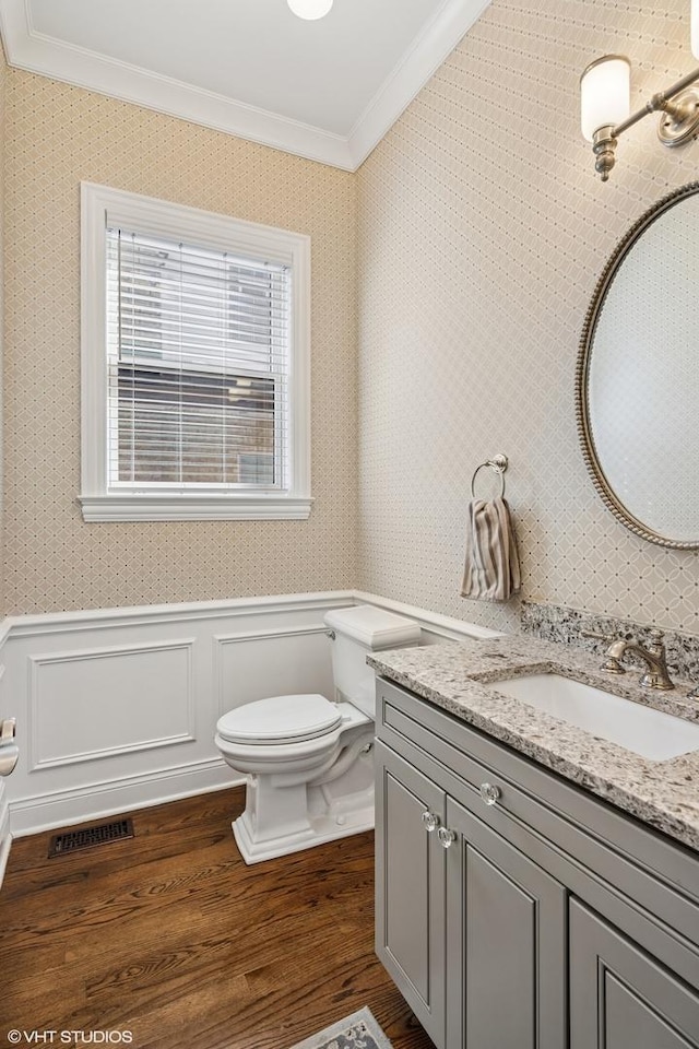bathroom featuring crown molding, wood finished floors, wainscoting, vanity, and toilet