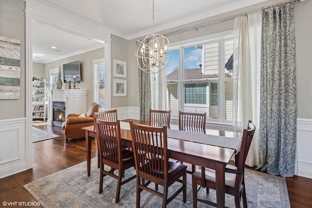 dining space featuring a decorative wall, ornamental molding, and a wainscoted wall