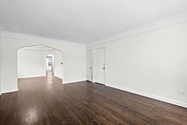 unfurnished room featuring baseboards, arched walkways, and dark wood-style flooring