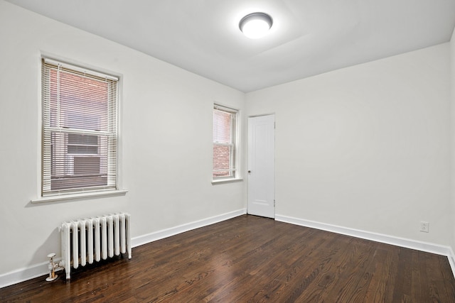 spare room featuring baseboards, radiator heating unit, and wood finished floors