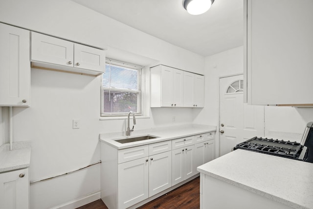 kitchen featuring stove, a sink, dark wood-type flooring, and white cabinetry