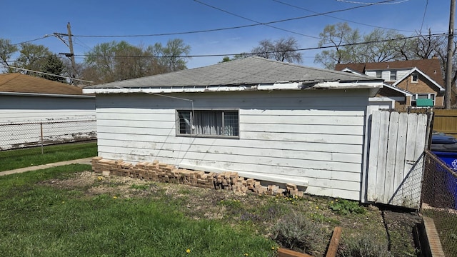 view of home's exterior featuring a yard, fence, and roof with shingles