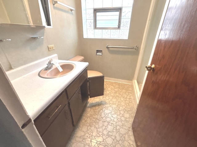 full bathroom with vanity, toilet, stone finish floors, baseboards, and a shower