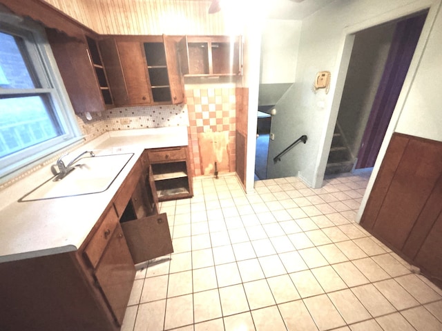kitchen with a sink, light tile patterned flooring, open shelves, light countertops, and tasteful backsplash