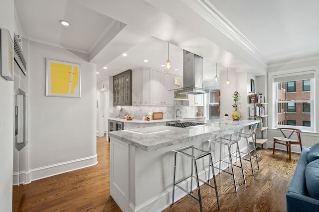 kitchen featuring crown molding, a kitchen breakfast bar, island range hood, and glass insert cabinets