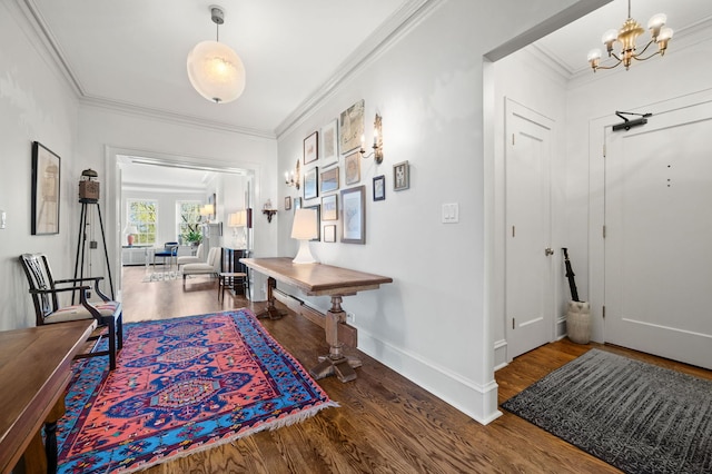corridor featuring crown molding, baseboards, wood finished floors, and a notable chandelier