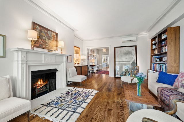 living area featuring wood finished floors, crown molding, a wall mounted AC, and a warm lit fireplace