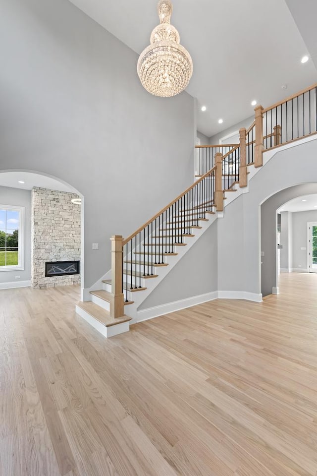 7213 Daybreak Ln, Long Grove, IL 60060 - unfurnished living room featuring a high ceiling, wood finished floors, stairway, a fireplace, and a chandelier
