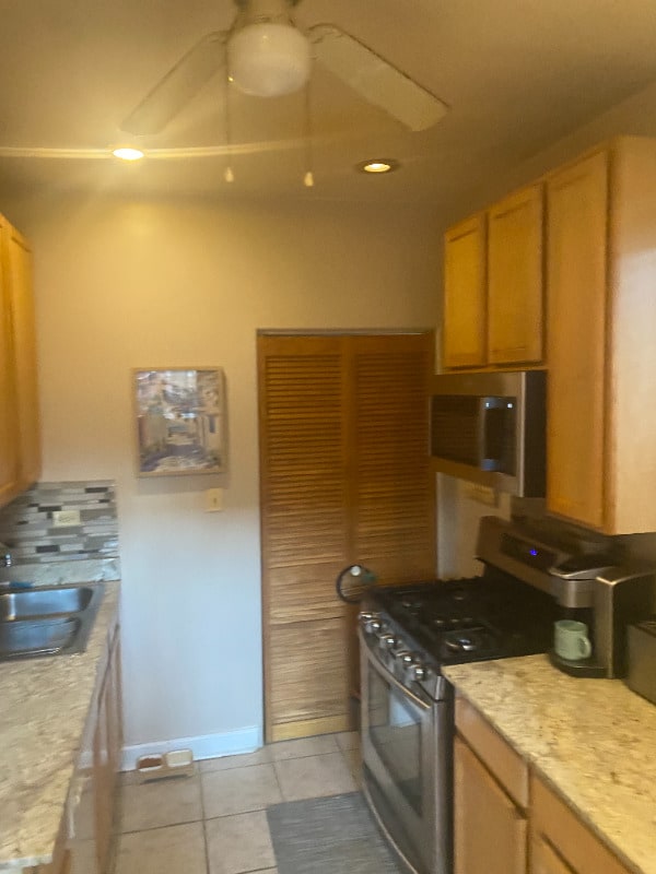7308 S Yates Blvd Unit 1, Chicago, IL 60649 - kitchen with appliances with stainless steel finishes, a sink, light countertops, baseboards, and light tile patterned floors