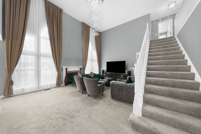 living area featuring a fireplace, carpet floors, and stairs