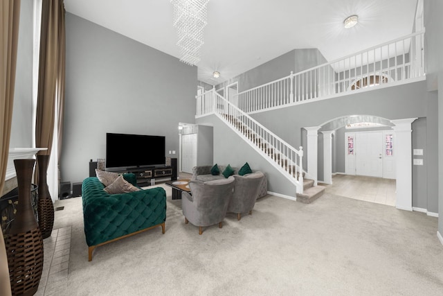 carpeted living room featuring arched walkways, baseboards, ornate columns, a high ceiling, and stairway