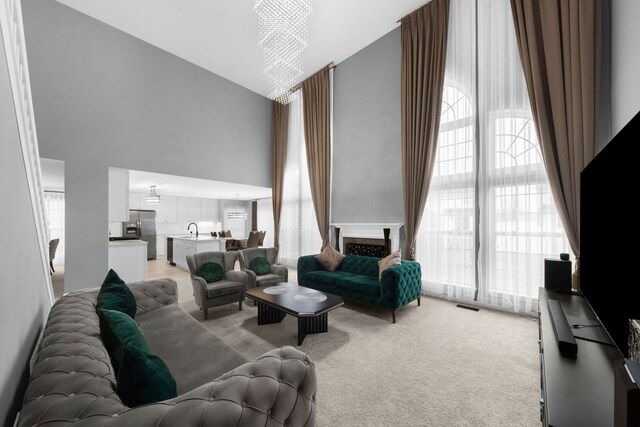 living room featuring visible vents, light carpet, a towering ceiling, and a wealth of natural light