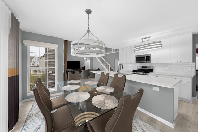 dining space with light wood finished floors, baseboards, and a notable chandelier