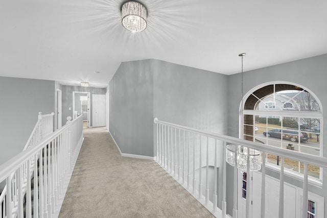 corridor with baseboards, carpet flooring, and a chandelier