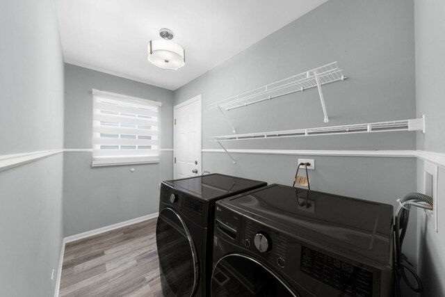 washroom featuring baseboards, wood finished floors, washer and clothes dryer, and laundry area