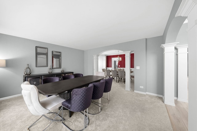 dining area with arched walkways, baseboards, light wood finished floors, and ornate columns
