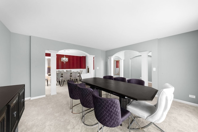 dining room featuring light carpet, arched walkways, a notable chandelier, and ornate columns
